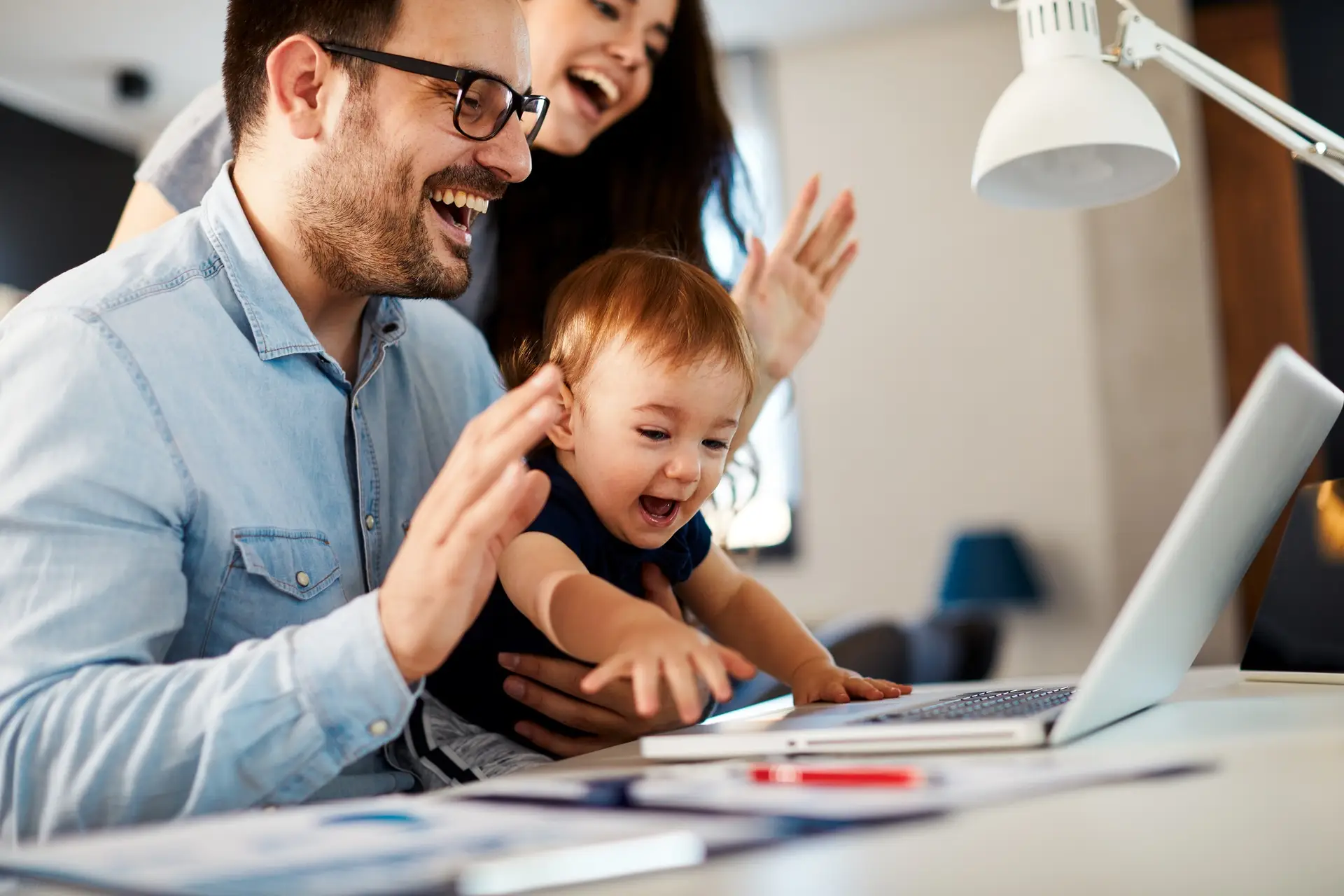 Young parents mom, dad and their toddler son have a video call via laptop at home